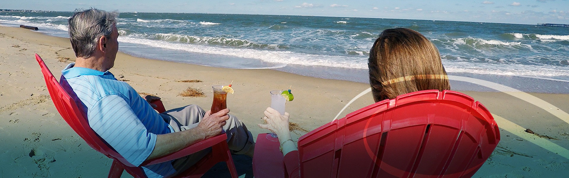 Retired Man and Woman Enjoying a Cocktail on the Sand