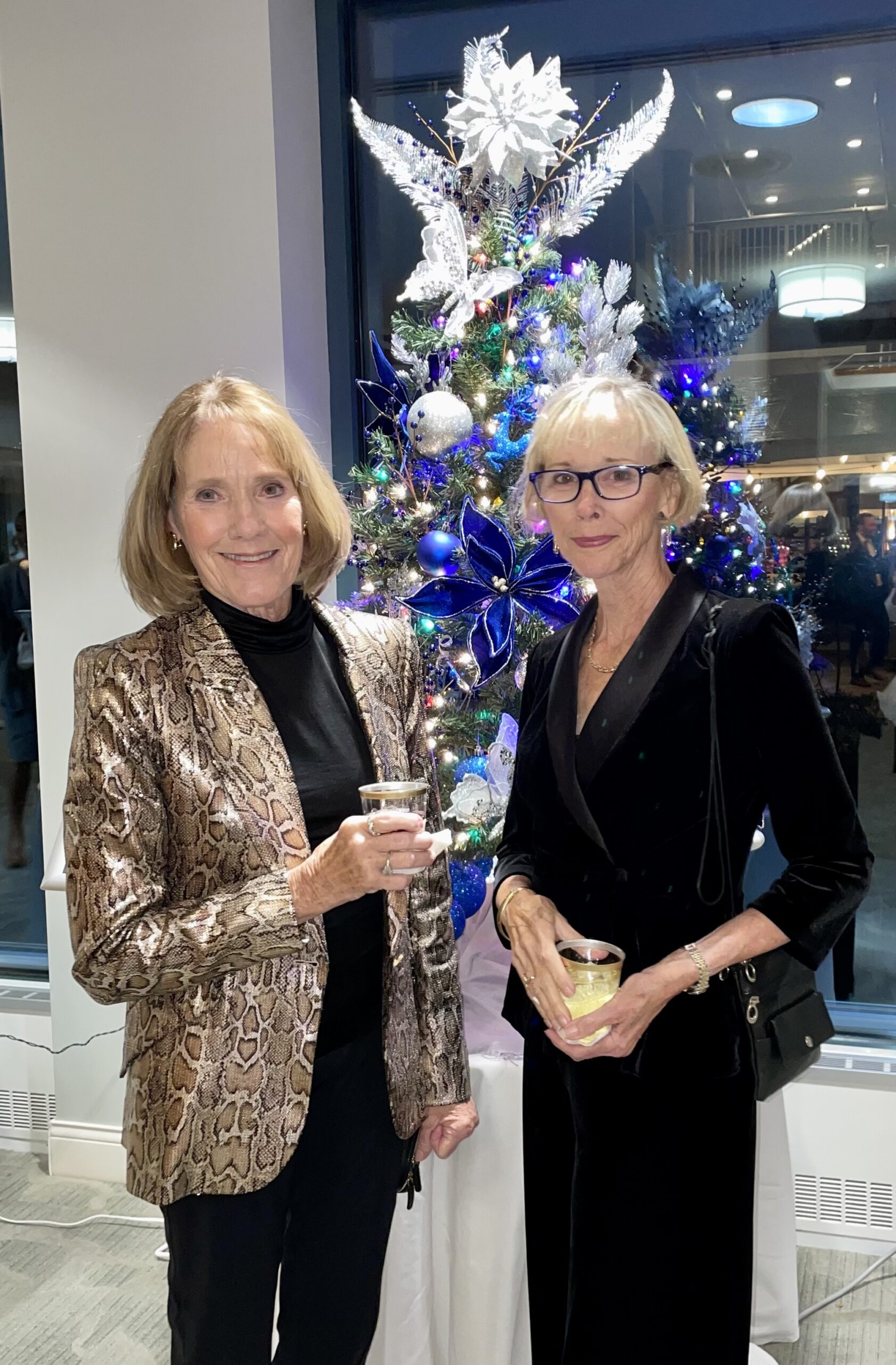 2 Woman Smiling in Front of Christmas Tree