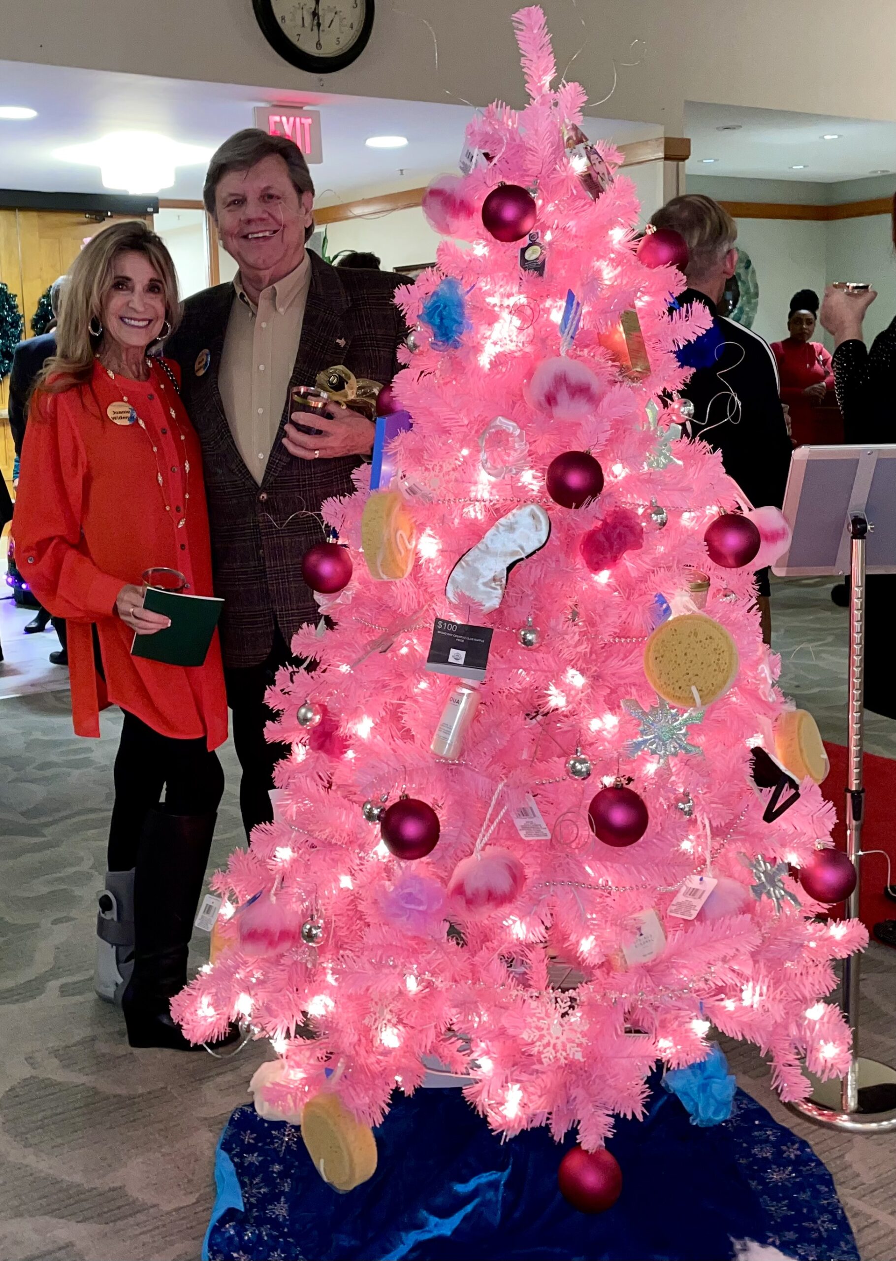 Man and Woman Smiling Behind Pink Christmas Tree