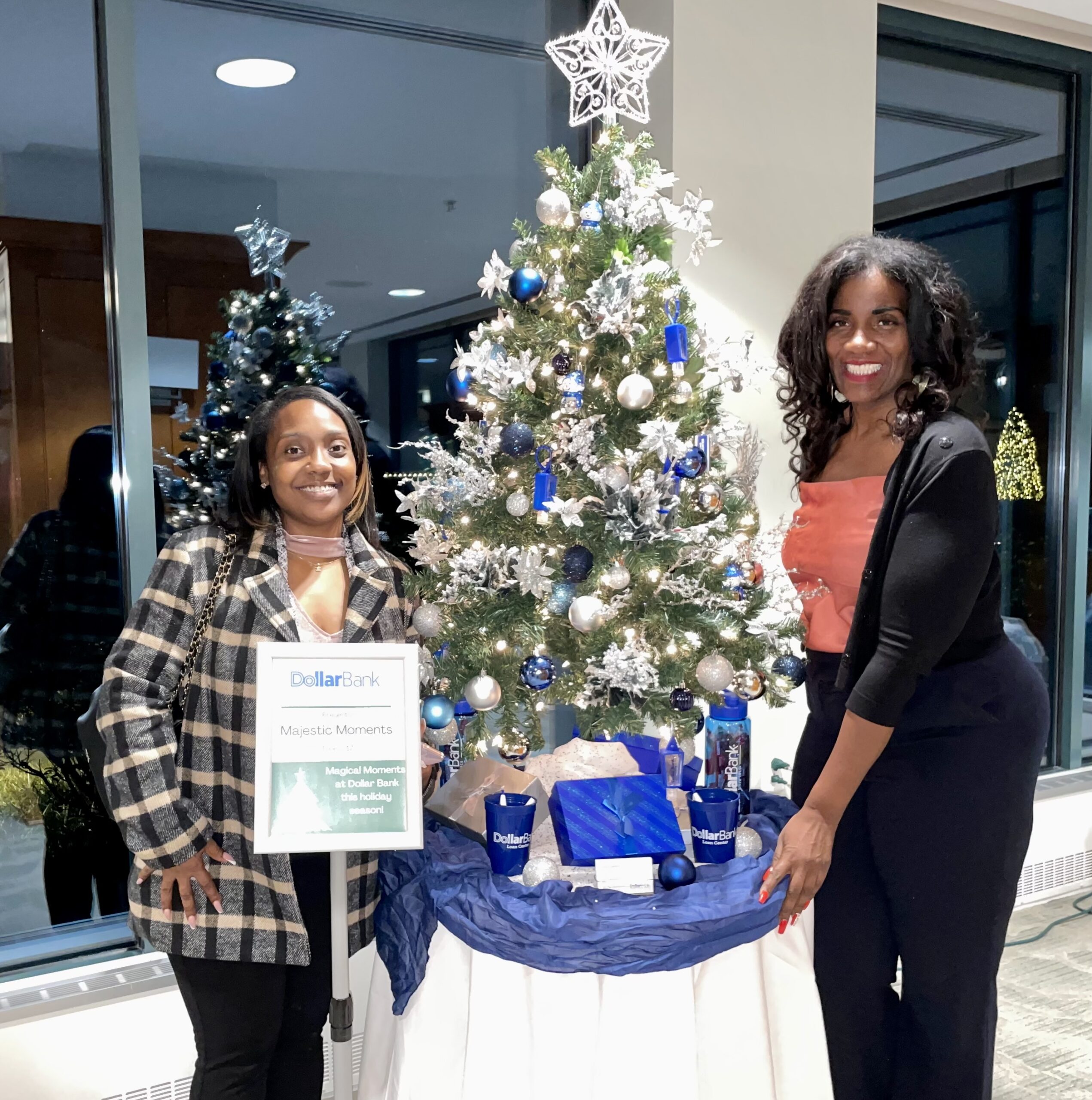 2 Woman Smiling Next to Christmas Tree