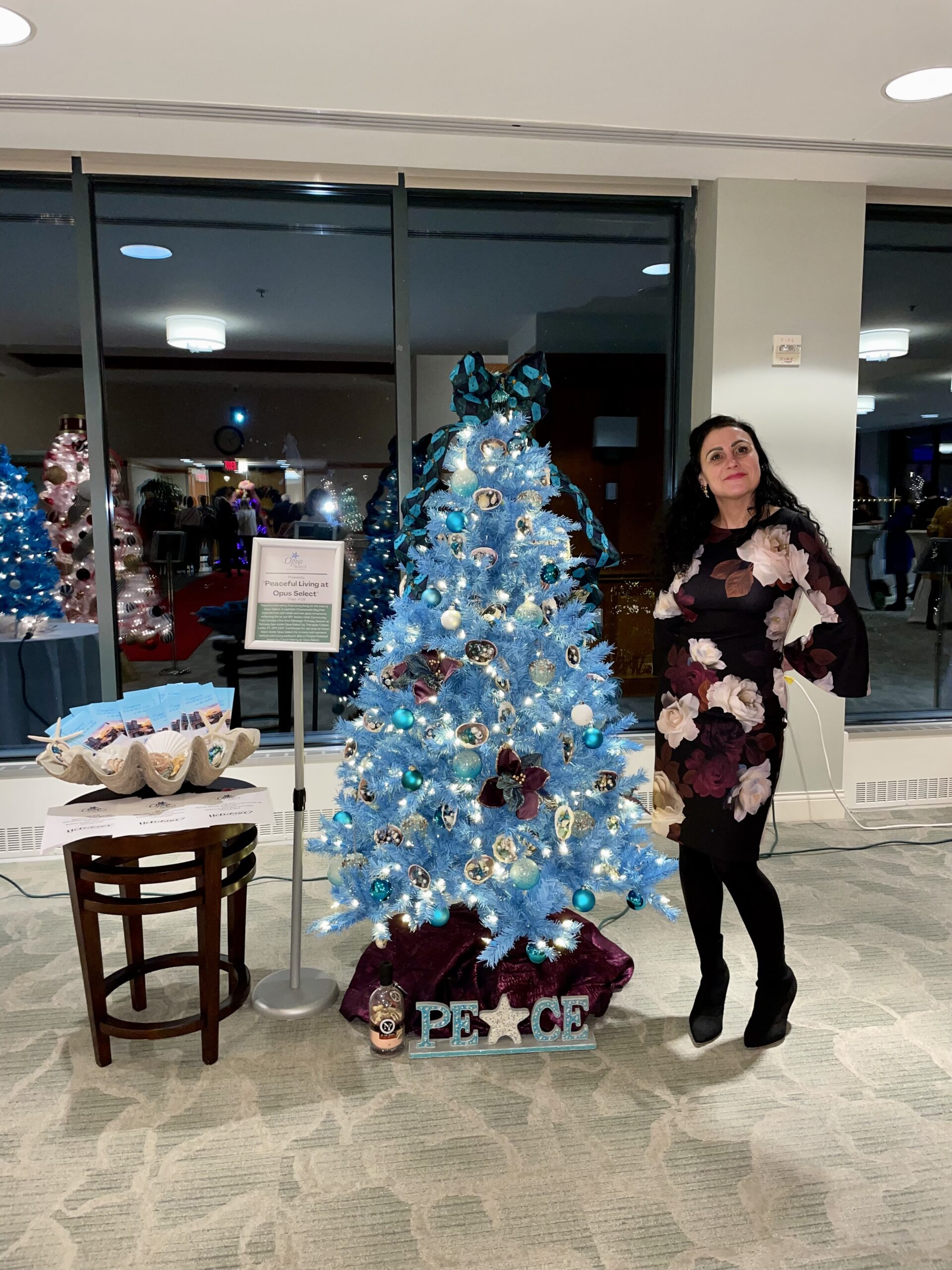 Woman Smiling Next to Blue Christmas Tree