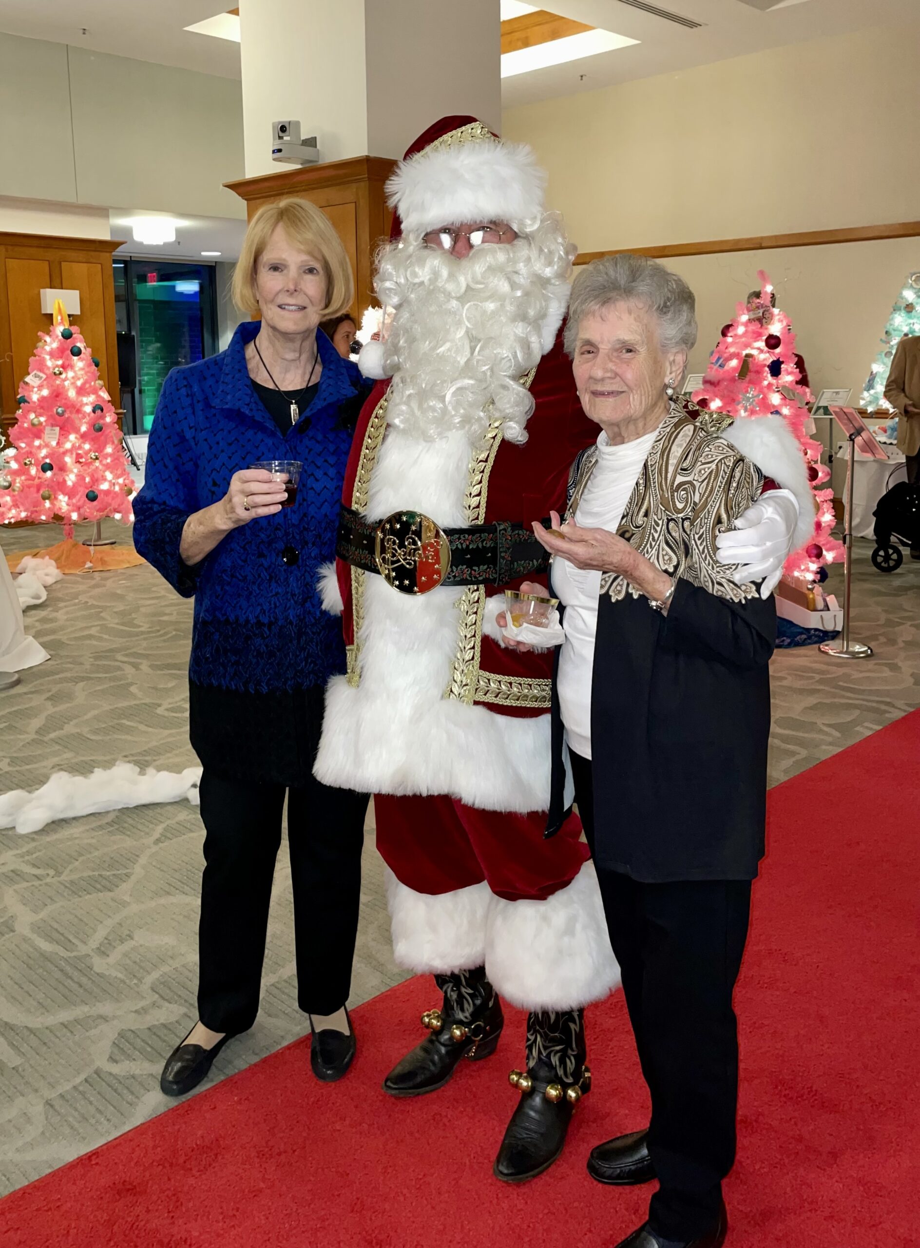 Woman Holding Drinks and Smiling with Santa Claus