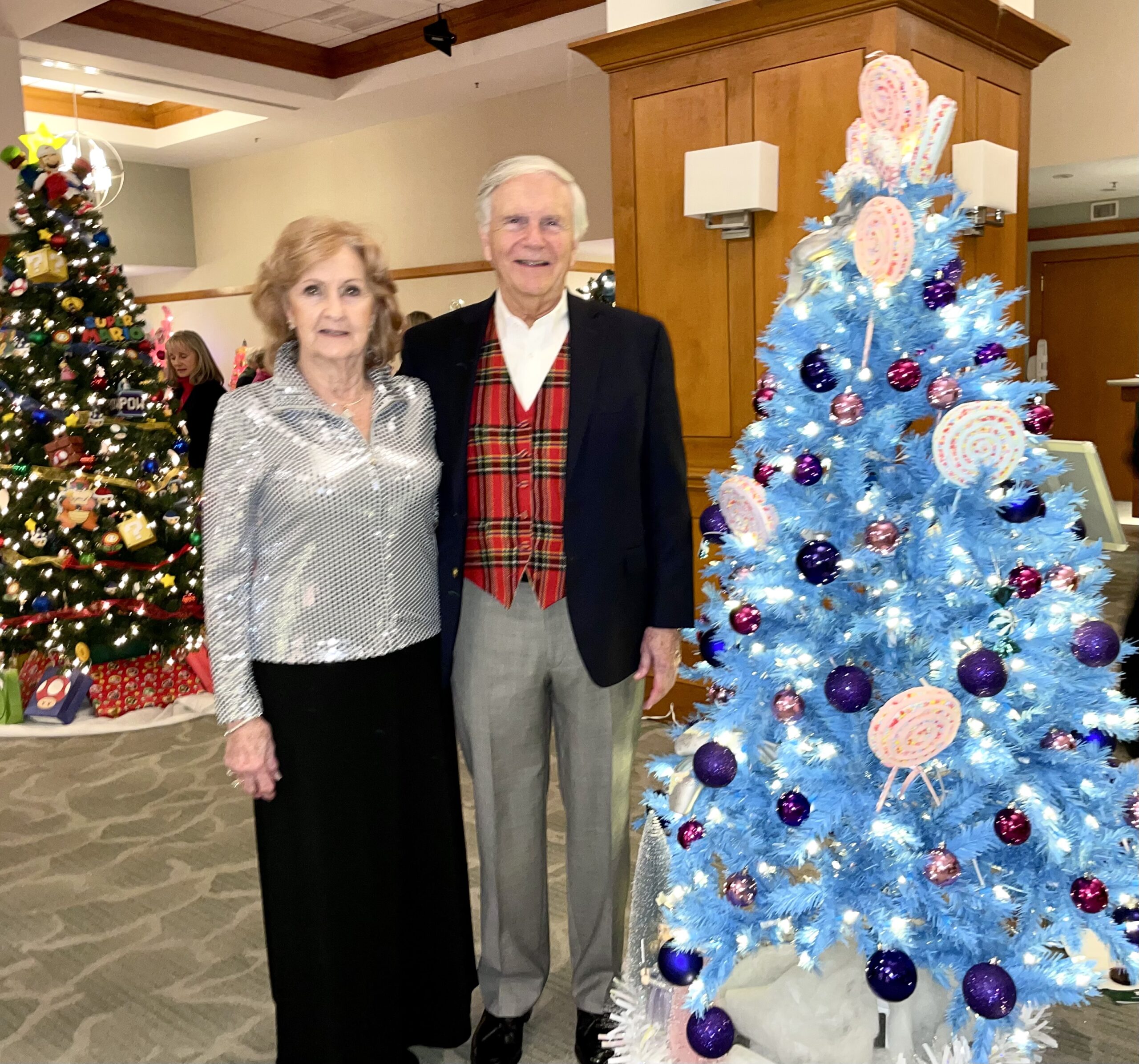 2 Party Guests Smiling Next to Blue Christmas Tree