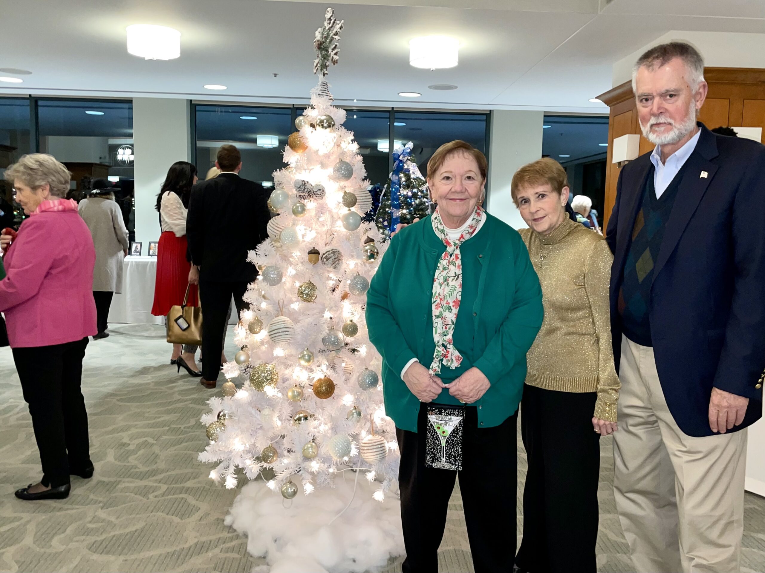 2 Woman and 1 Man Smiling in Front of a White Christmas Tree