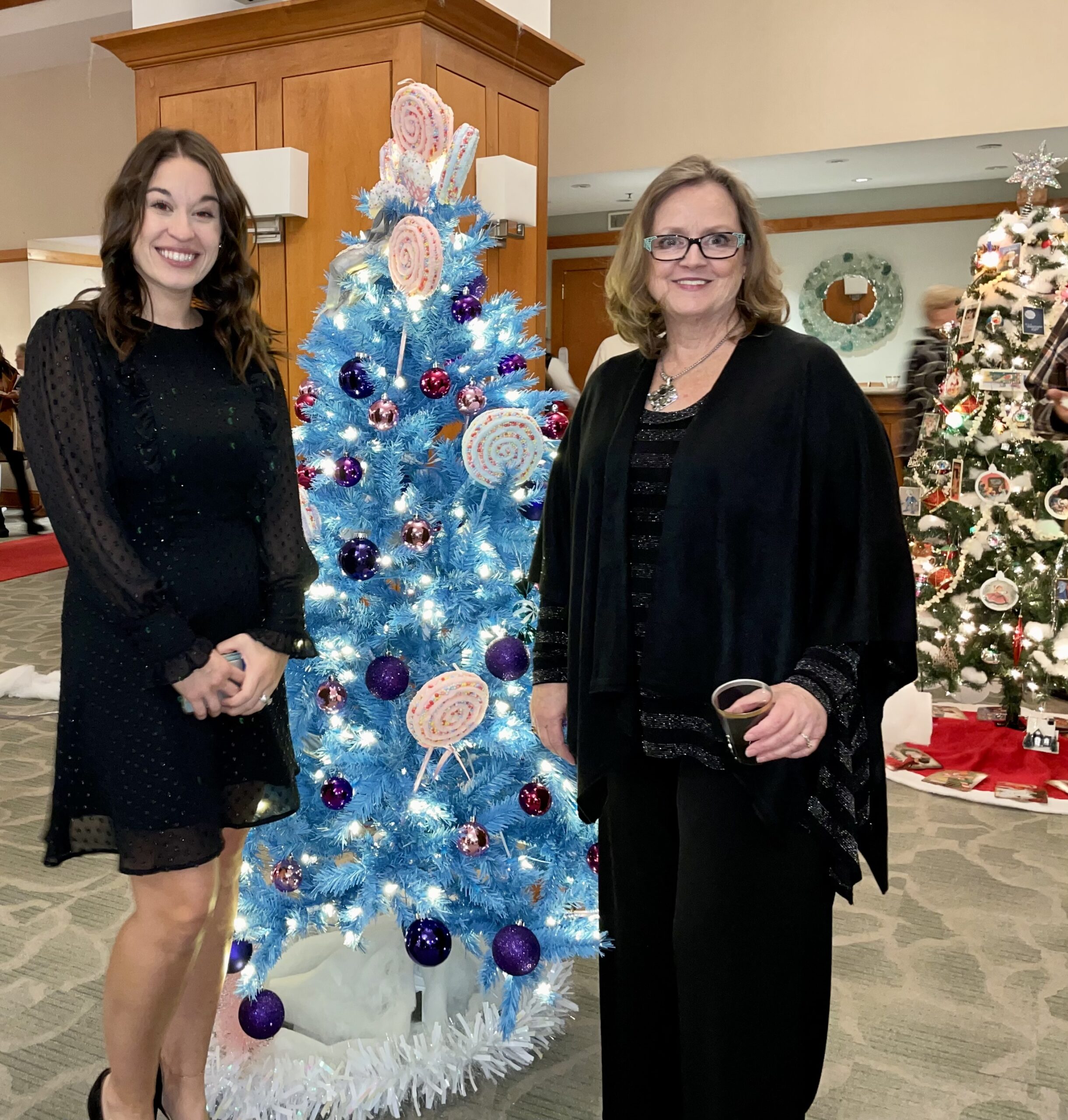 2 Woman Smiling in Front of Christmas Tree