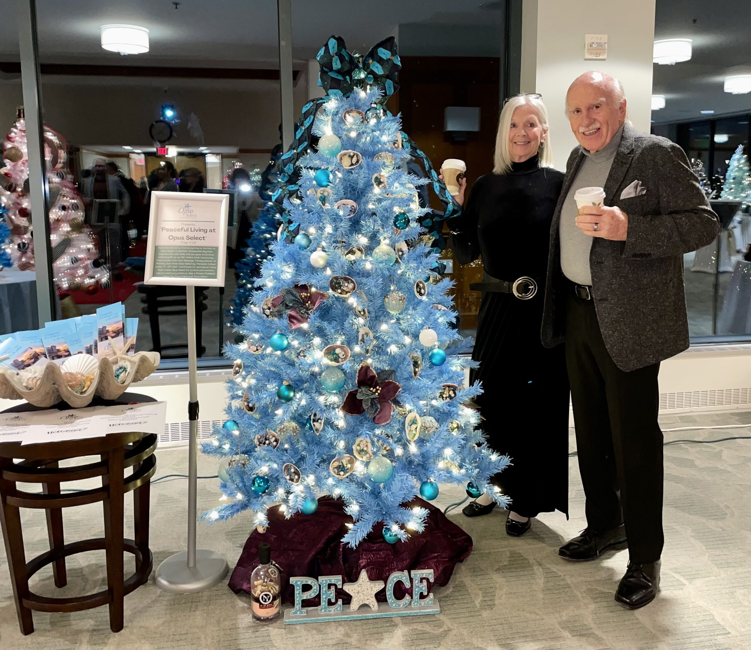 Man and Woman Smiling in Front of Blue Christmas Tree