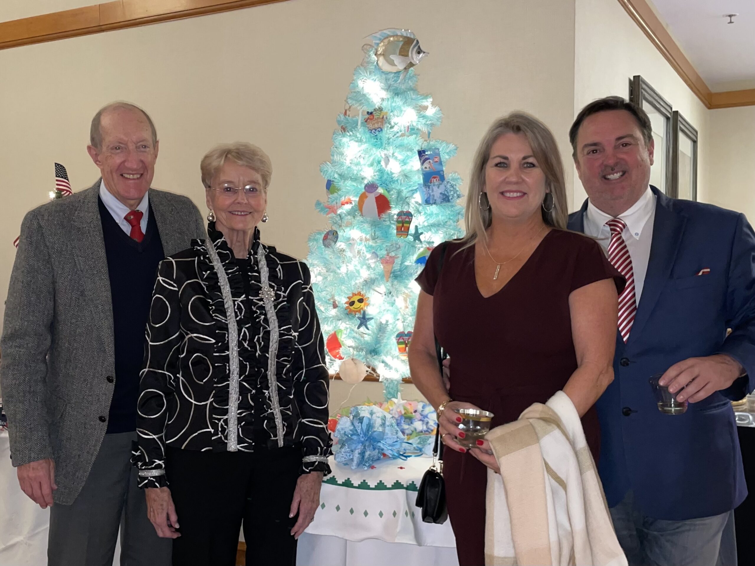 Group of People Smiling in Front of a Small Christmas Tree