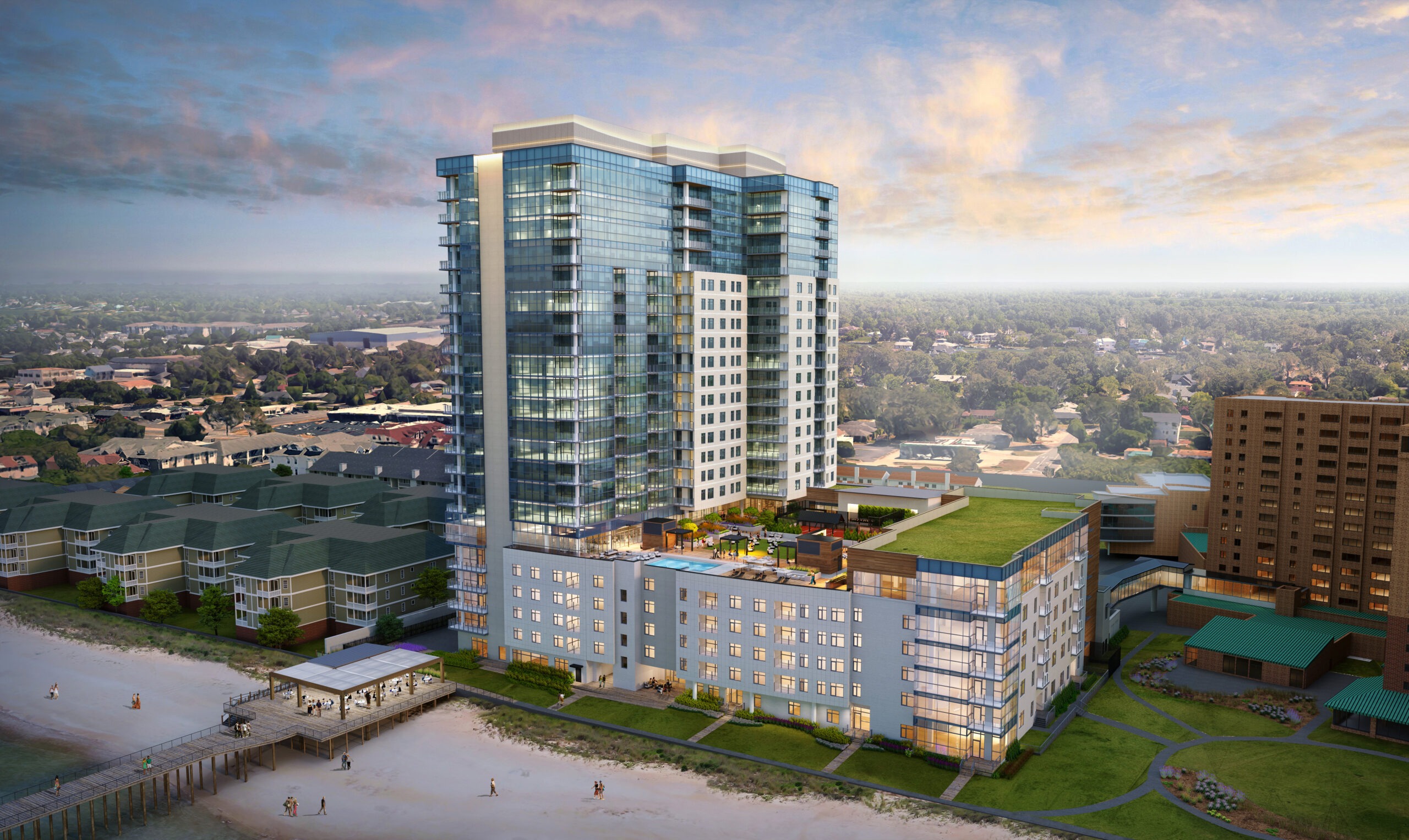 A modern beachfront high-rise building with glass windows and a rooftop garden overlooks a sandy beach. The sky is partly cloudy, and the surrounding area is a mix of greenery and urban landscape.