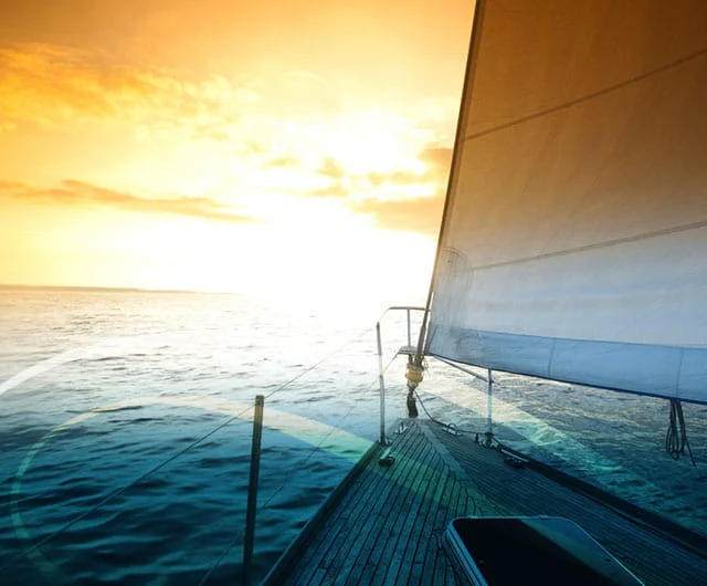 A boat gliding through the water at sunset, with warm orange tones illuminating the sky near the WCC Senior Living Community