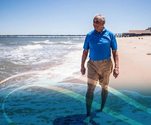 A man walking along a sandy beach, with waves gently lapping at the shore