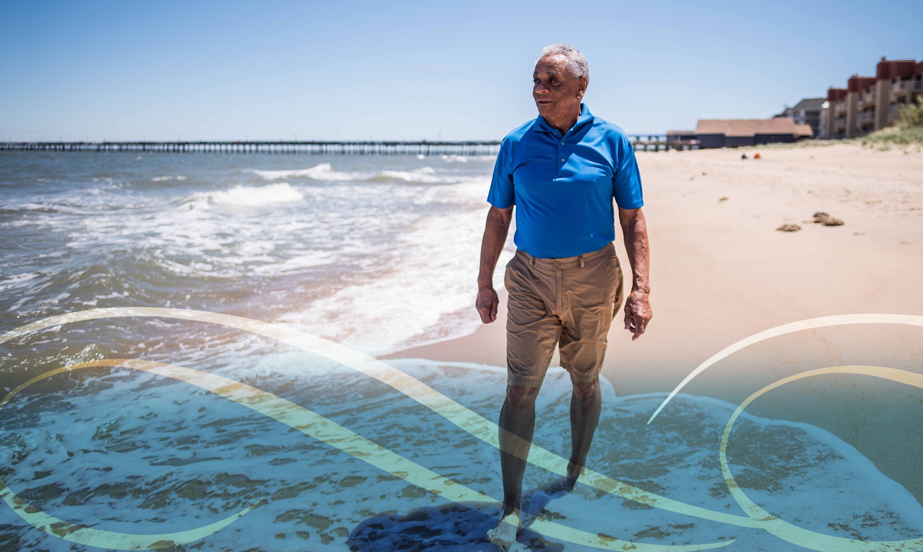 A man walking along a sandy beach, with waves gently lapping at the shore