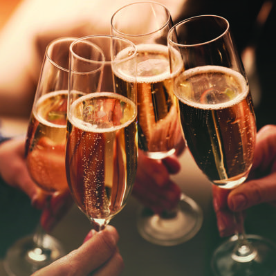 Four individuals cheerfully holding glasses of champagne, celebrating a special occasion together.