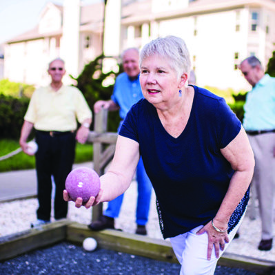 A senior woman holds a vibrant purple ball, exuding joy and warmth in her expression.